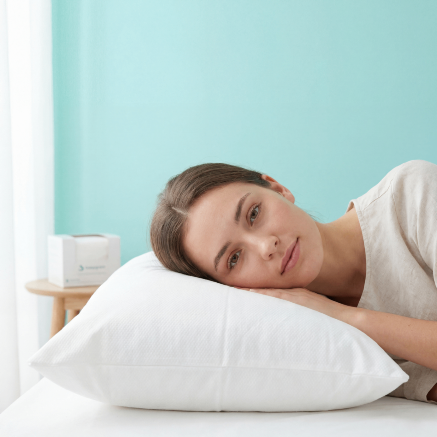 Woman resting on a fresh Sleepgram pillowcase with box on nightstand